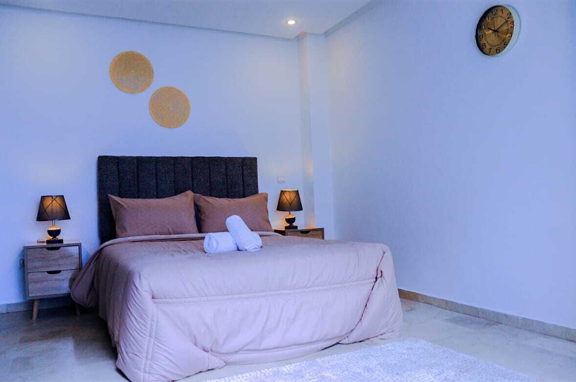 A bedroom with a large bed, two bedside tables, and a wall clock.