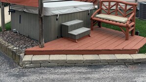 Un jacuzzi con cubierta de madera, escalones, un banco y un área techada con un letrero que dice 