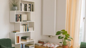 A living room with a white bookshelf, a green armchair, a wooden floor, and a window with curtains. - Charming Leseloft vacation apartment in Tiengen (Waldshut-Tiengen)
