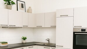 A modern kitchen with white cabinets, a black countertop, and a stainless steel oven. - Charming Leseloft vacation apartment in Tiengen (Waldshut-Tiengen)
