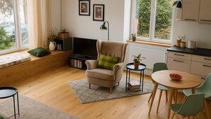A cozy living room with a sofa, a small table, a TV, and a window with a view of greenery. - Charming Leseloft vacation apartment in Tiengen (Waldshut-Tiengen)