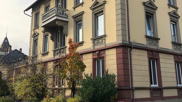 A multi-story building with a balcony on the second floor, surrounded by greenery and a stone wall. - Charming Leseloft vacation apartment in Tiengen (Waldshut-Tiengen)