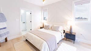 A modern bedroom with a bed, bedside tables, a mirror, and a view of the outside.
