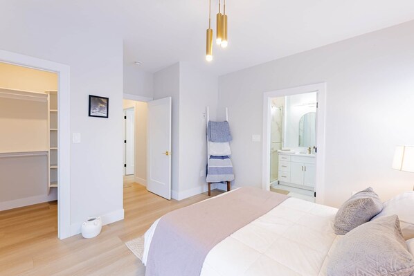 A bedroom with a bed, a wardrobe, a bathroom with a mirror, and a hallway.