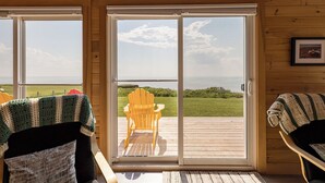 A room with a sliding glass door leading to an outdoor deck with a chair. - Red Cliff Escape with Beach Access (Albany)