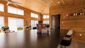 A wooden interior with a bar area, ceiling fans, and large windows. - Red Cliff Escape with Beach Access (Albany)