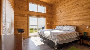 A bedroom with a bed, a desk, a chair, and a large window. - Red Cliff Escape with Beach Access (Albany)