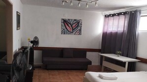 A hotel room with a bed, a desk, a couch, and a fan. - Porto Central Hostel (Porto)