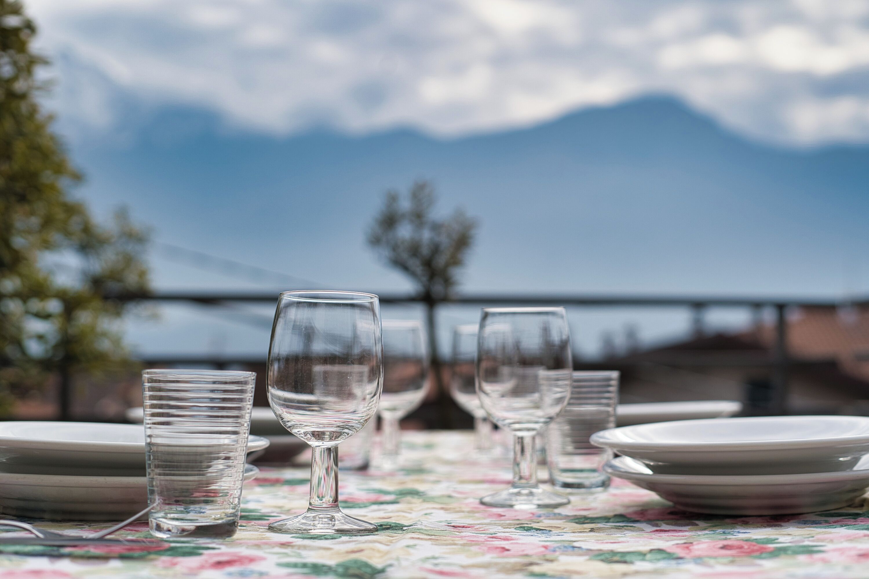 Una mesa servida con platos y vasos, con vistas a un paisaje montañoso.