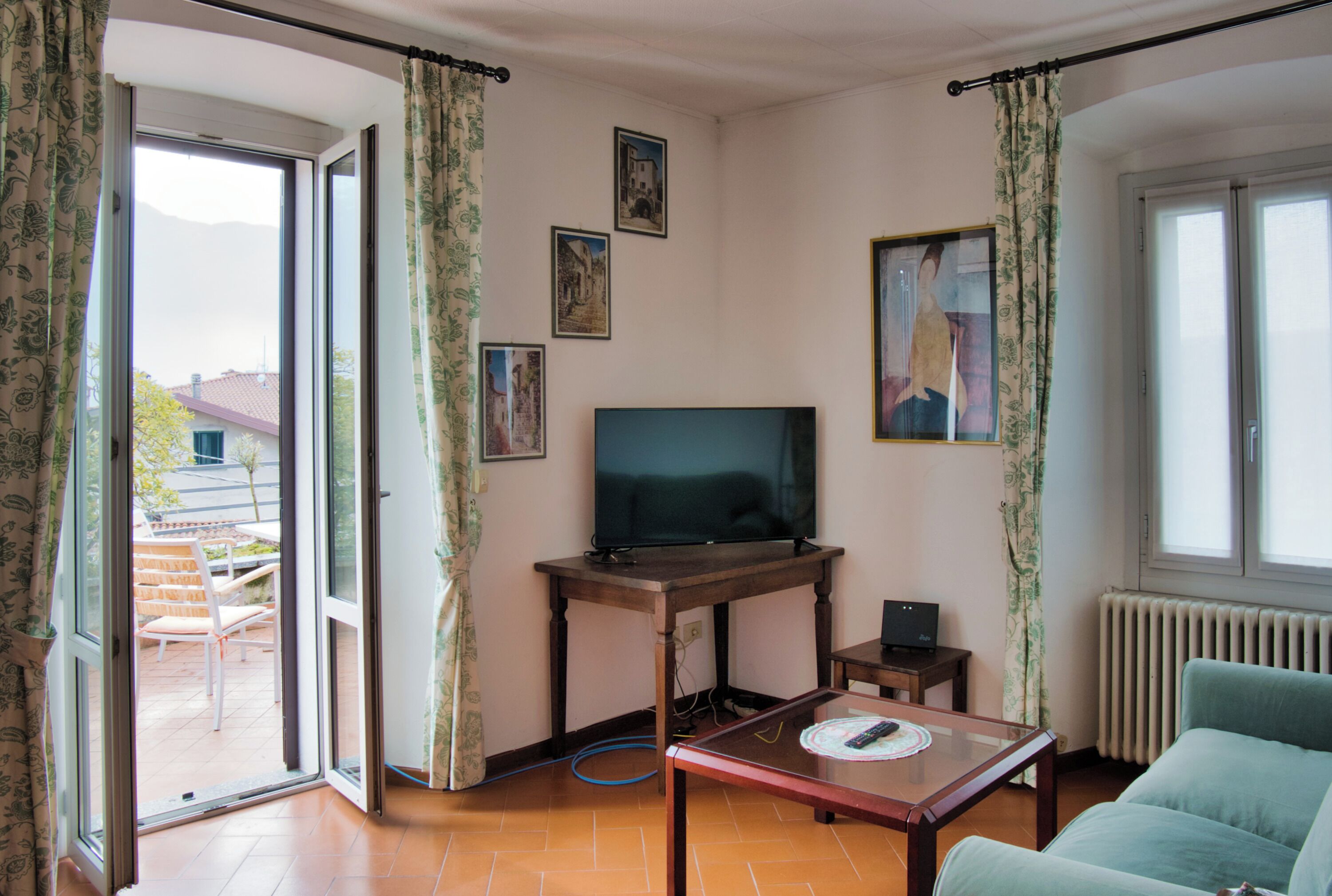 Un salon avec un téléviseur posé sur une table en bois, un canapé et une vue sur l’extérieur.