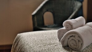 Un lit recouvert d’une couvre-lit à motifs, une fenêtre donnant sur les montagnes et une chaise placée dans un coin.