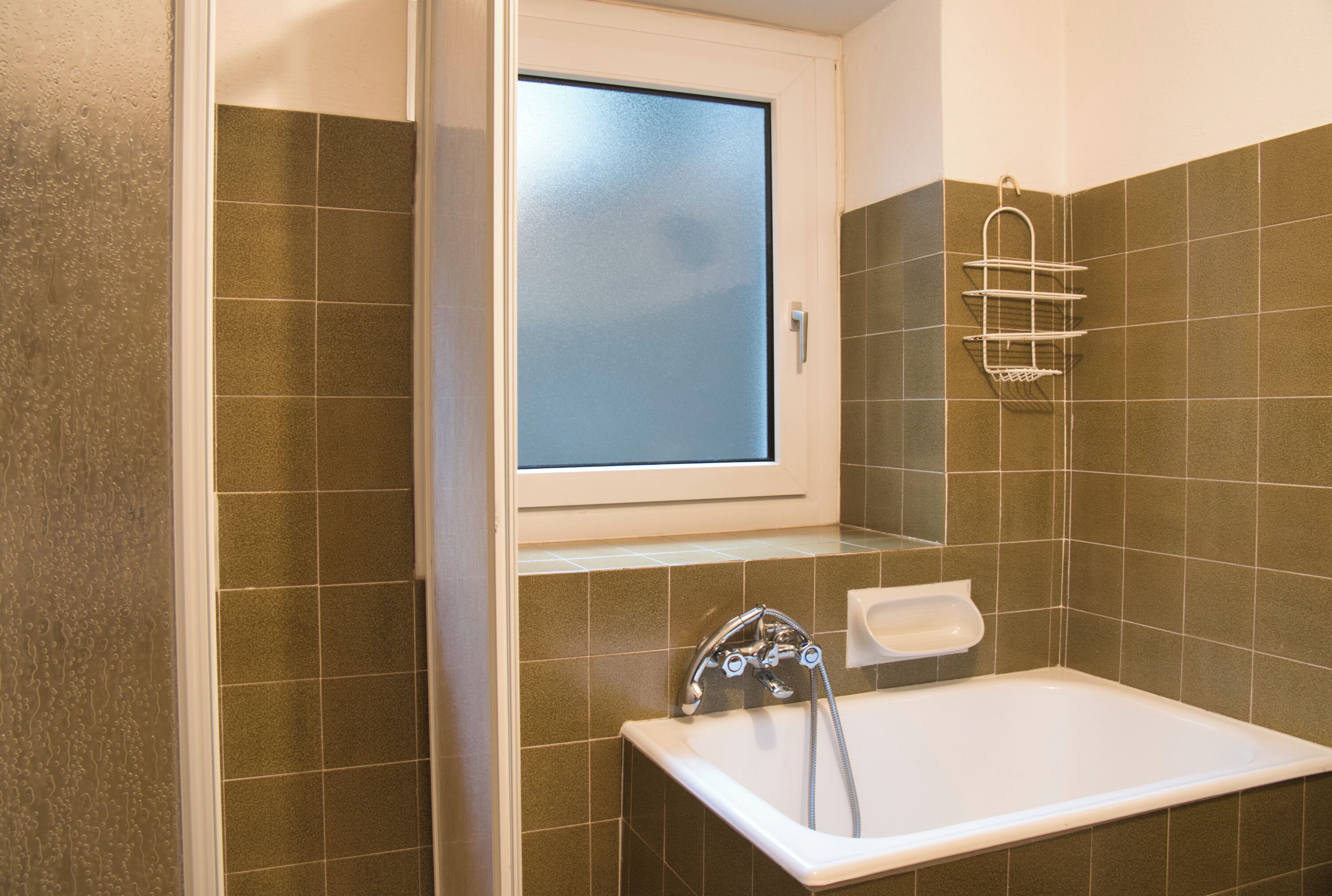 A bathroom with a bathtub, a window, and a towel rack.