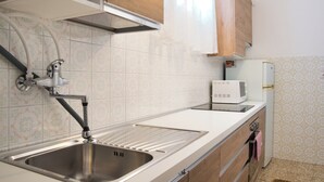 Una cocina con un lavamanos de acero inoxidable, un microondas y armarios de madera.