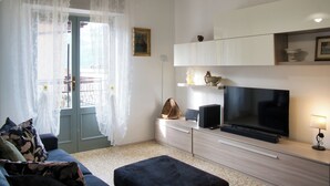 Una sala de estar con sofá, televisor y mesa de comedor.
