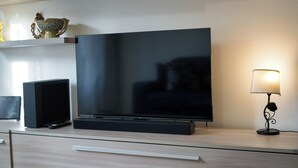 Un televisor de pantalla plana sobre un mueble de madera, con una lámpara a su lado.