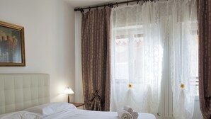 Una habitación de hotel con una cama bien hecha, un cuadro en la pared y una ventana con cortinas.
