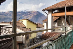Un barrio residencial con montañas al fondo, con casas de techo de teja y un balcón con barandilla de metal.