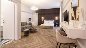 Ein modernes Hotelzimmer mit einem großen Bett, einer Couch, einem Schreibtisch und einem Spiegel.