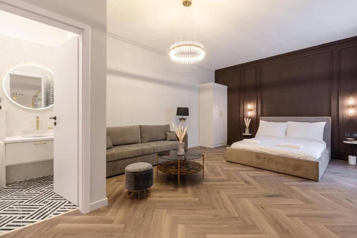 Une chambre moderne avec un grand lit, un canapé, une table basse ronde et un miroir.