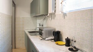 Una cucina compatta con forno a microonde, macchina del caffè e lavandino.