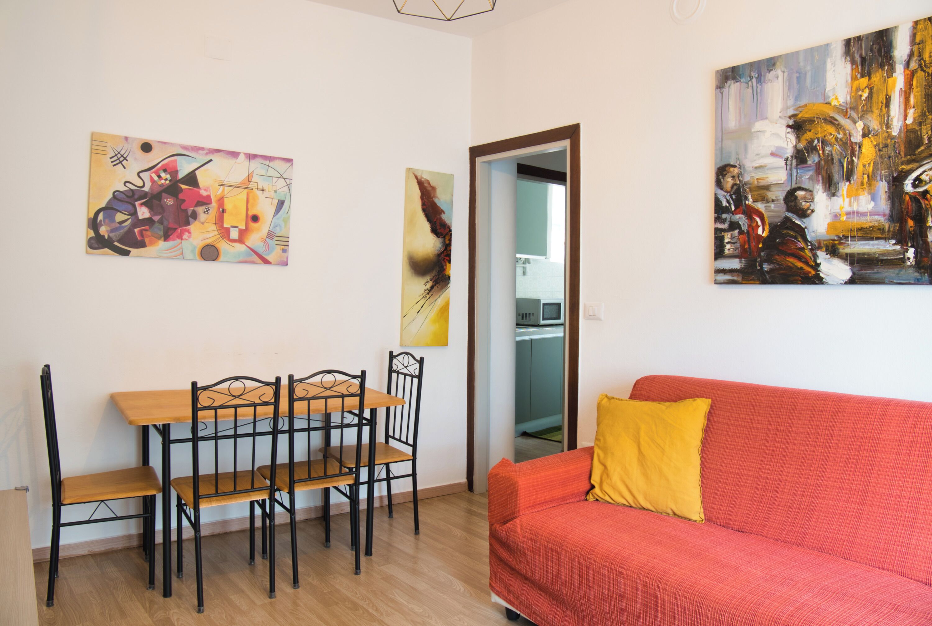 Ein Zimmer mit einem Esstisch, Stühlen, einem roten Sofa und zwei Bildern an den Wänden.