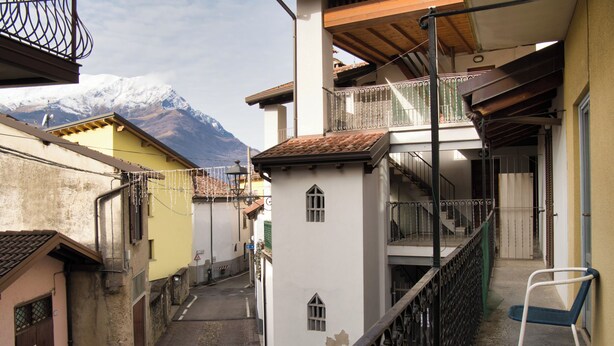 Un vicolo stretto fiancheggiato da edifici, con una ringhiera metallica e una sedia.