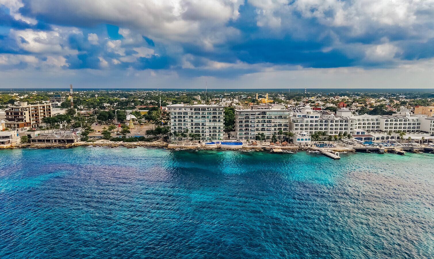 A coastal hotel with multiple buildings, a pier, and a clear view of the sea.