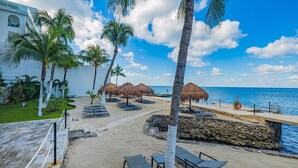 Ett semesterparadis vid stranden med palmer, solstolar och parasoller av halmtak.