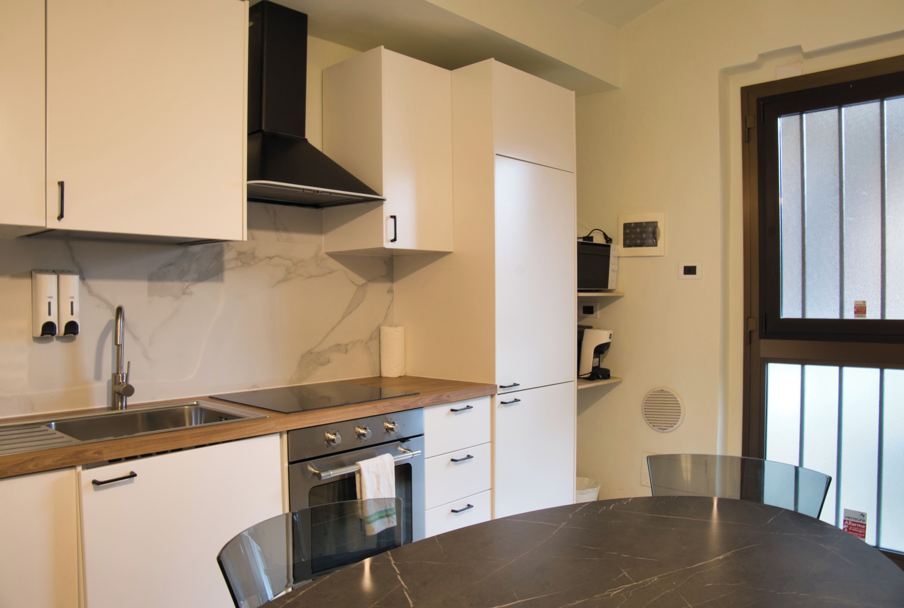 Una cocina moderna con encimera de mármol, pileta de acero inoxidable y horno empotrado.