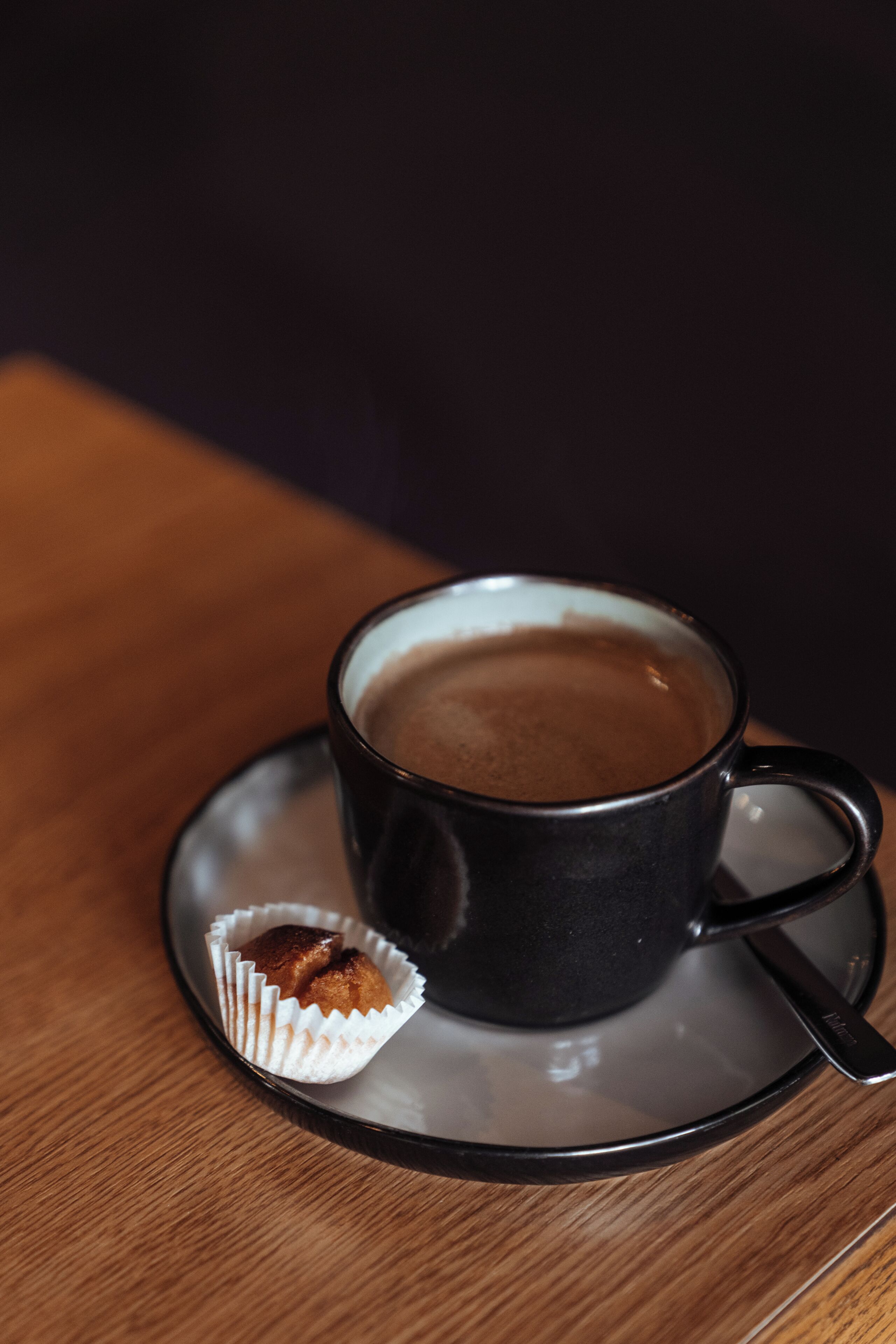 Una taza de café sobre un plato con un muffin en una mesa de madera.