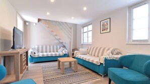 Ein modernes Wohnzimmer mit Treppe, zwei Sofas, einem Couchtisch und einem Fernseher.