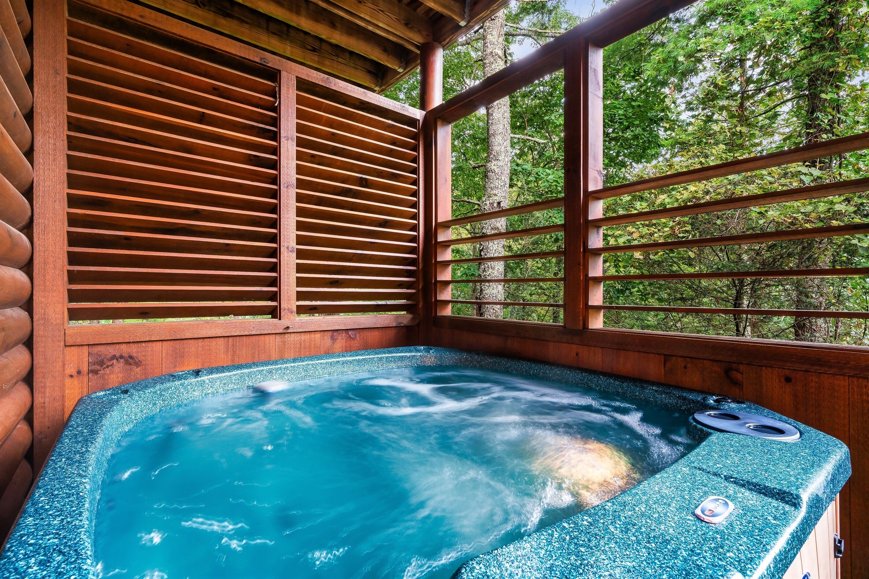 A hot tub in a wooden cabin with a view of trees.