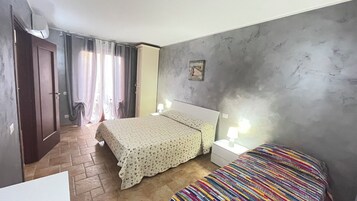 Un dormitorio con cama, mesita de noche, lámpara, puerta y ventana con cortinas.