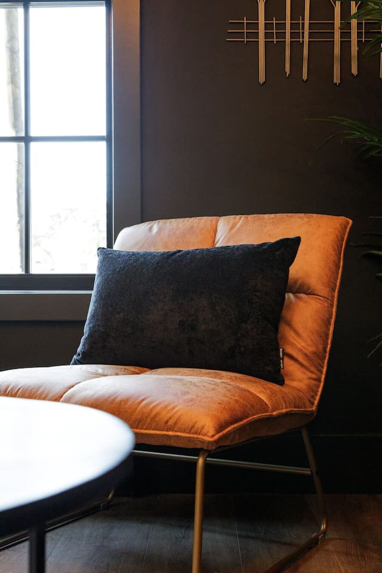 Une chaise moderne avec un siège et un dossier en cuir, placée à côté d’une table ronde.