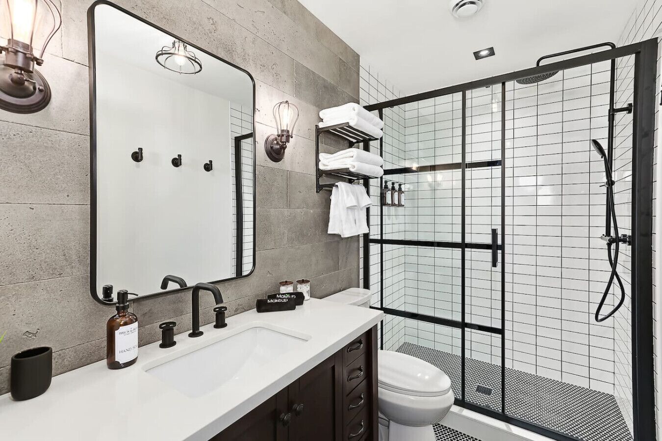 A modern bathroom with a large mirror, a sink, a toilet, and a glass-enclosed shower area.