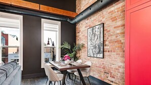 Un comedor con pared de ladrillo, una puerta roja y un ventanal grande.