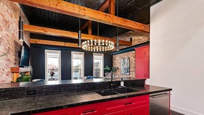Una cocina moderna con armarios rojos, encimera negra y vigas de madera a la vista.