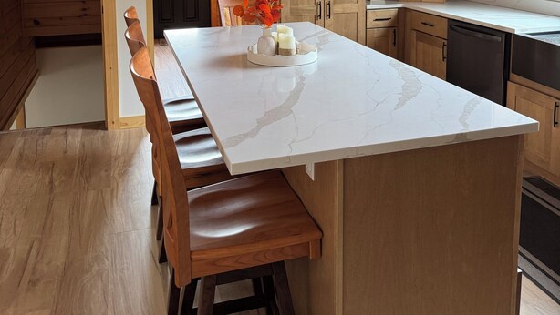 Una cocina moderna con armarios de madera, encimera de mármol y un banco empotrado.