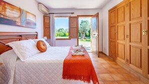 A bedroom with a bed, a window, a door, and a wardrobe. - Can Calistro: Rural Villa with Private Tennis Court (Selva)