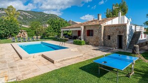 A pool, outdoor seating, a ping pong table, and a stone building with a red door. - Can Calistro: Rural Villa with Private Tennis Court (Selva)