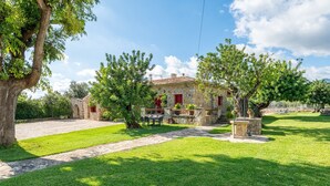 A stone building with a red roof, a paved driveway, and a well-maintained lawn. - Can Calistro: Rural Villa with Private Tennis Court (Selva)