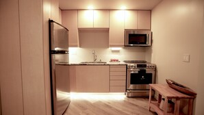 A compact kitchen with a refrigerator, microwave, stove, and wooden table. - European Lakeside Oasis on 100+ Acres (Park Hills)