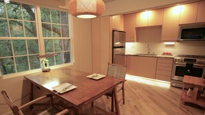A modern kitchen with wooden cabinets, a built-in oven, and a dining area with a wooden table and chairs. - European Lakeside Oasis on 100+ Acres (Park Hills)