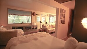 A bedroom with a large bed, a sofa, a desk, and a window with a view of trees. - European Lakeside Oasis on 100+ Acres (Park Hills)