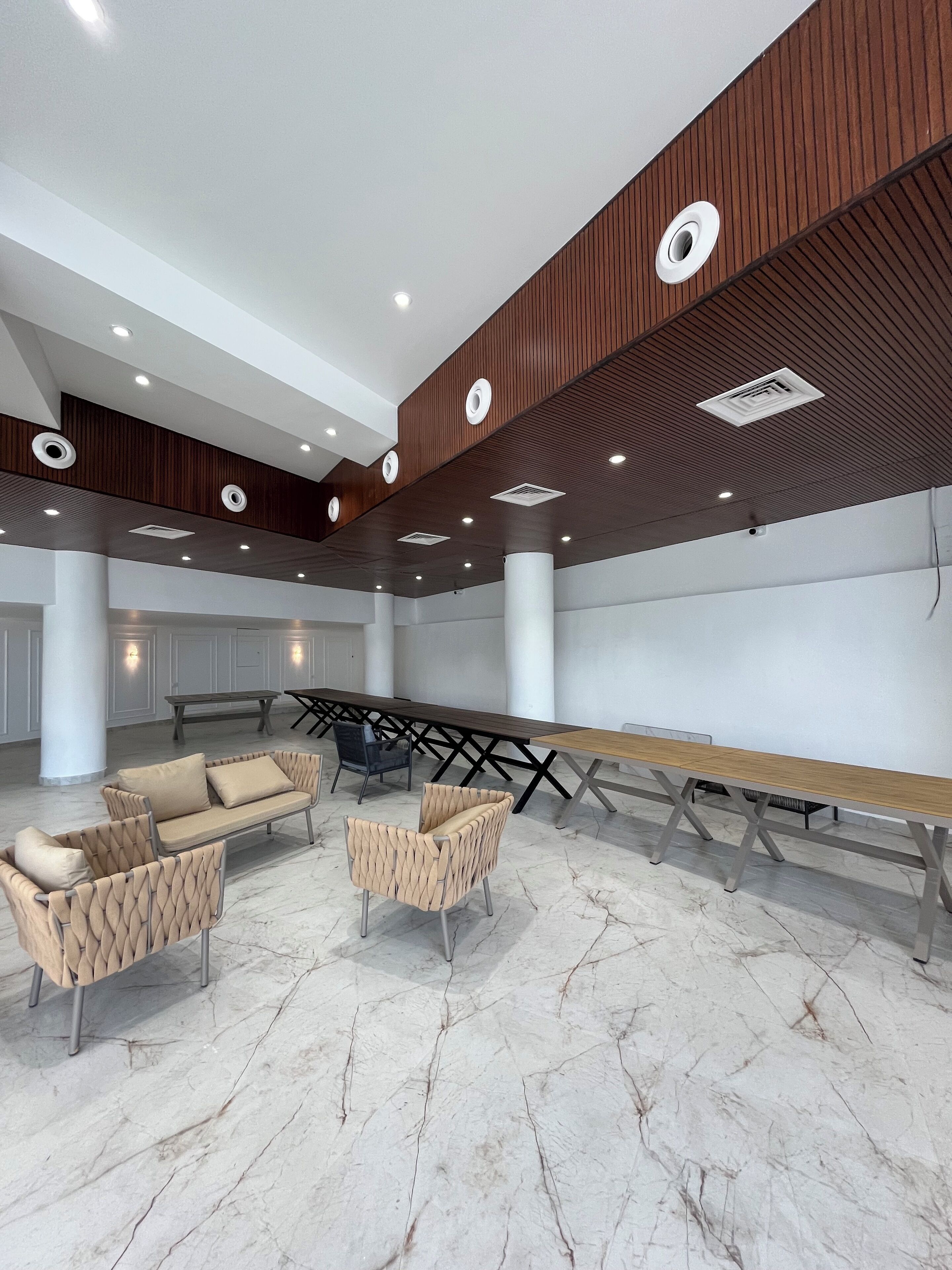 A spacious conference room with a long table, multiple chairs, and a high ceiling with recessed lighting.