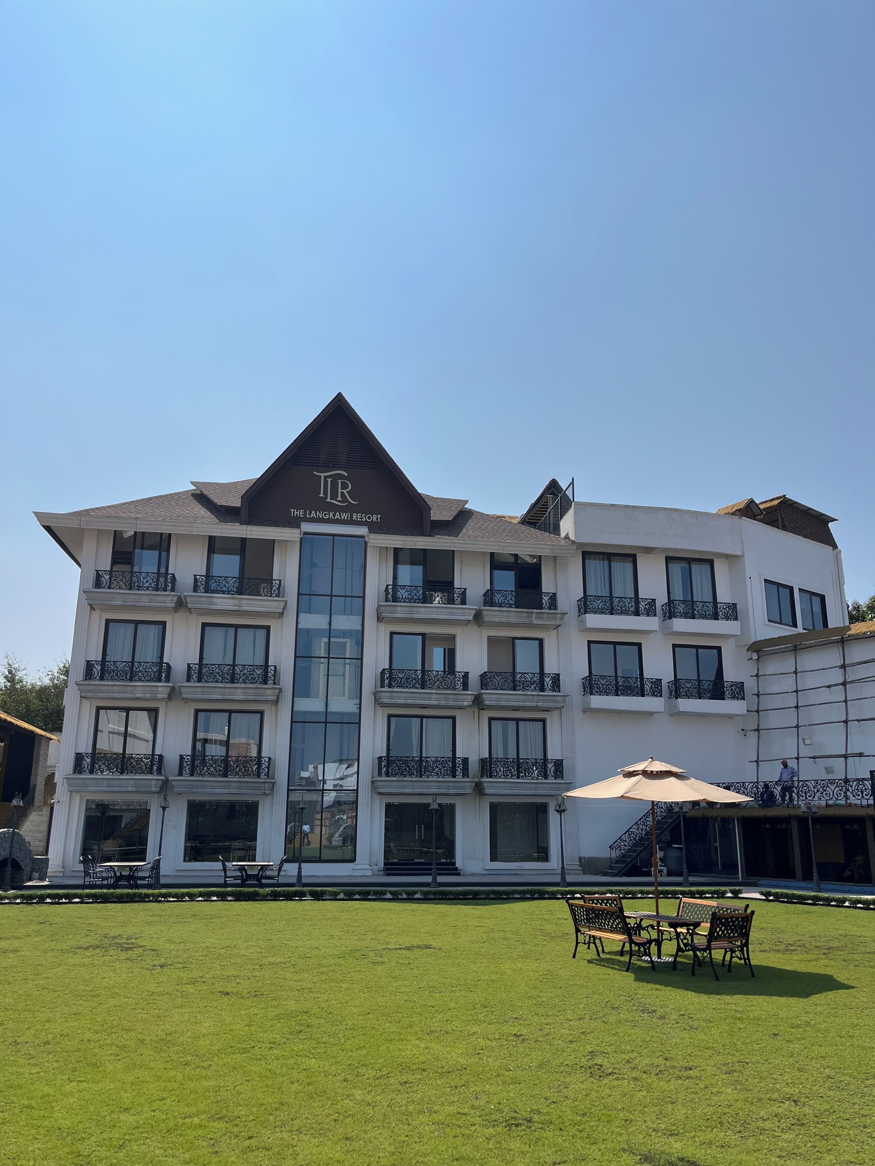 Een meerhoog gebouw met balkons, een centrale ingang en een bord met de tekst 'The Langkawi Resort'.