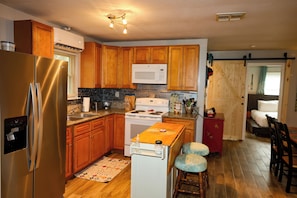 A kitchen with wooden cabinets, a stainless steel refrigerator, a microwave, and a stove. - Lake Cabin• 20 Min to River & Whitewater•Dogs OK! (Canyon Lake)