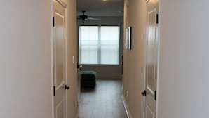 A narrow hallway with white doors, a ceiling fan, and a window with blinds. - The Purrfect Stay—a charming, cat-themed 2.5-bedroom home in Maryville, TN. (Maryville)