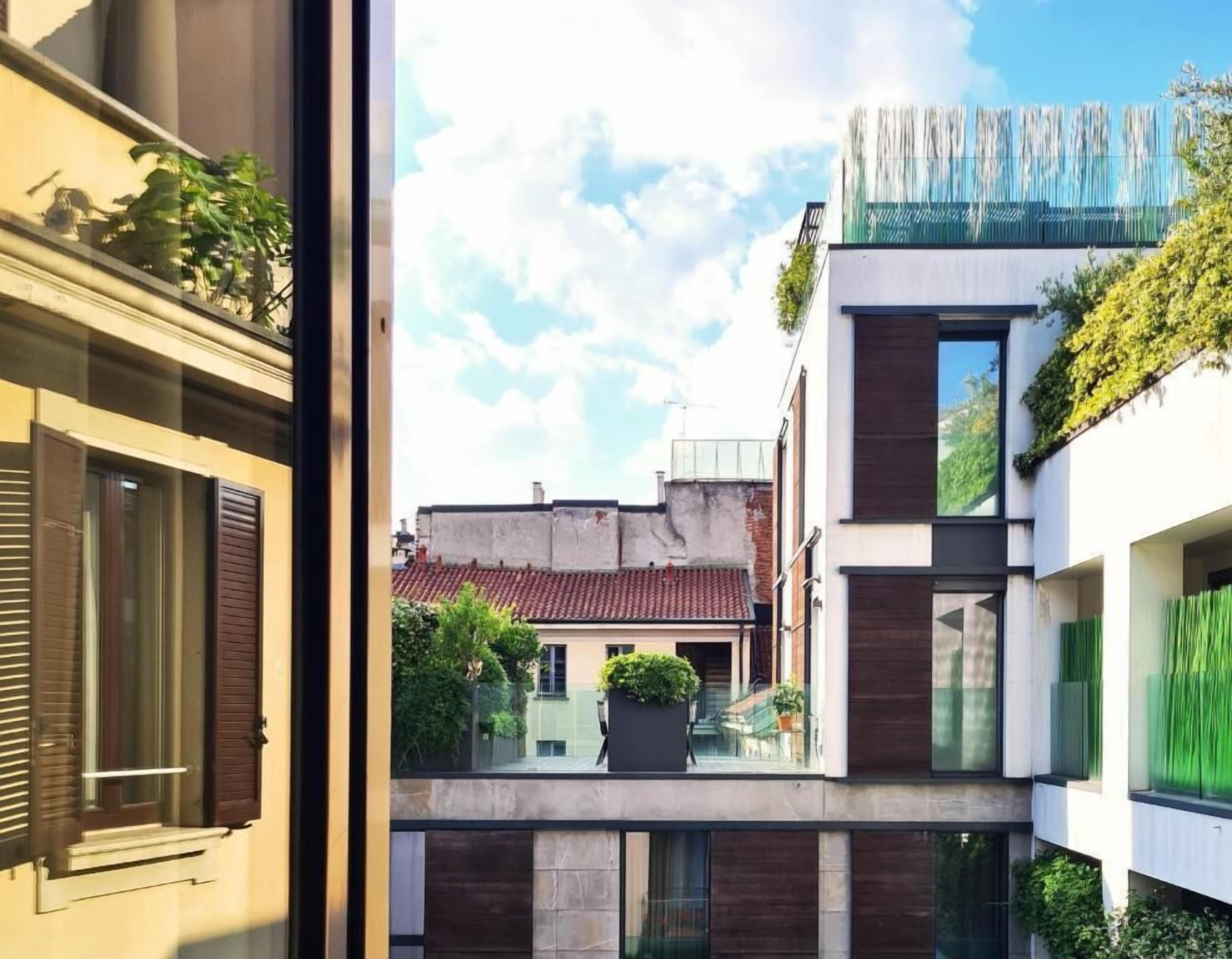 A modern building with a balcony, a view of neighboring buildings, and a clear sky.