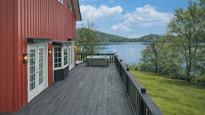 A red building with a wooden deck and a hot tub overlooking a lake. - Seneca Lake Barndominium Retreat (Quaker City)